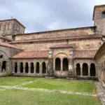 Claustro de la Colegiata de Santillana del Mar: capiteles, historia y visita Vista panorámica del patio y las cuatro galerías del claustro de la Colegiata de Santa Juliana en Santillana del Mar