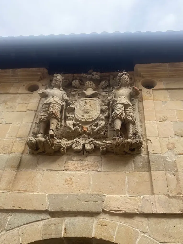 Escudo barroco de los Villa en la Casa de los Hombrones de Santillana del Mar, con sus dos tenantes armados