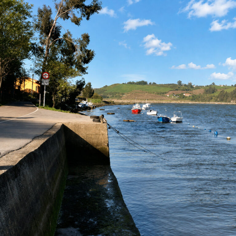 Pequeño embarcadero de Los Cantos en Suances con barcas amarradas en la ría y el camino de acceso junto al agua