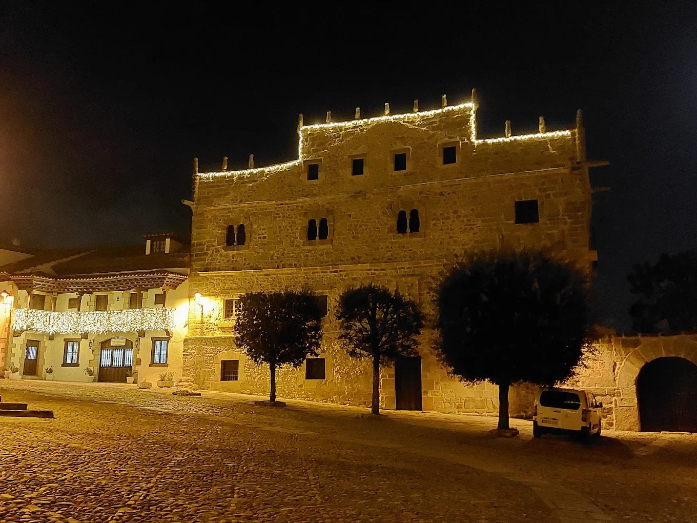 Fachada trasera del Palacio de Velarde en Santillana del Mar iluminada de noche, con su hastial escalonado