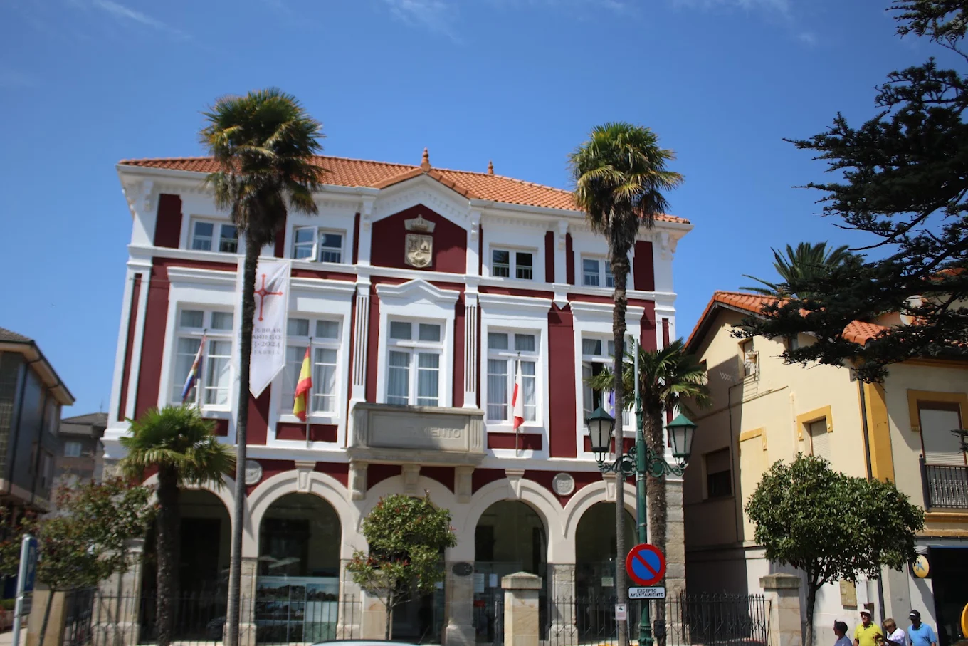 Vista general del Ayuntamiento de Suances desde la plaza de Viares en un día soleado, con las palmeras que flanquean la fachada