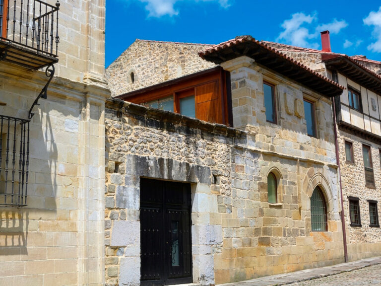 Fachada de piedra de la Casa de los Alonso en Santillana del Mar, con portalada en arco y dos pequeñas ventanas de traza gótica junto a la puerta