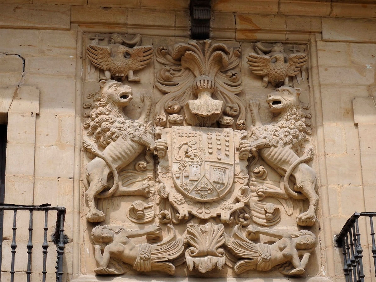 Detalle del escudo cuartelado de la Casona de los Tagle en Santillana del Mar, flanqueado por dos leones rampantes y coronado por dos águilas