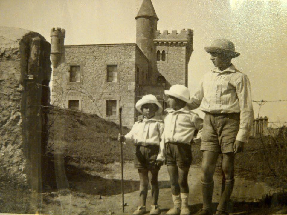 Fotografía antigua de 1912 con tres niños posando frente al castillo de Ceruti recién construido, en Suances