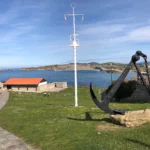 Recinto de El Torco de Suances con el histórico mástil de semáforo, un ancla y el mar Cantábrico al fondo