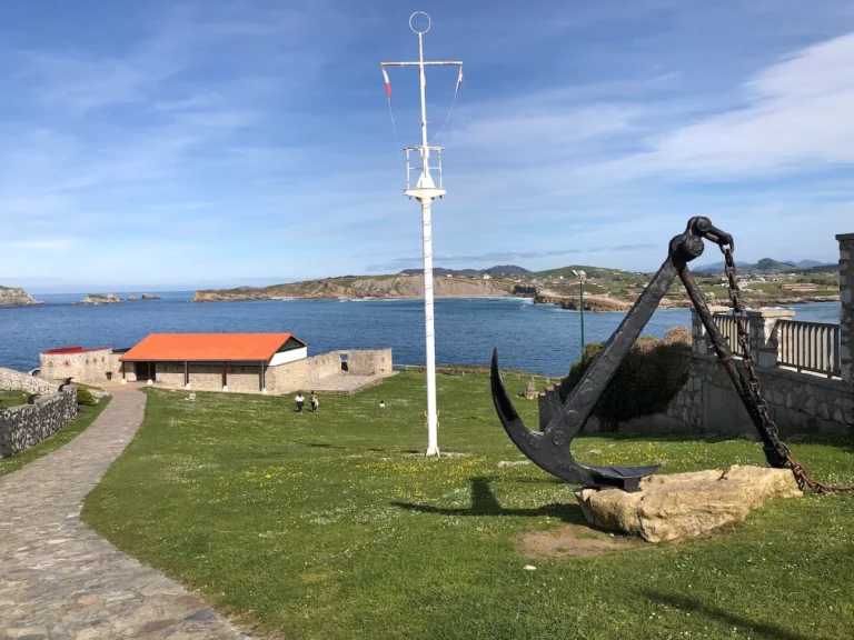 Recinto de El Torco de Suances con el histórico mástil de semáforo, un ancla y el mar Cantábrico al fondo