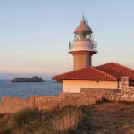 Faro de Suances al atardecer con la vivienda del torrero y un islote al fondo
