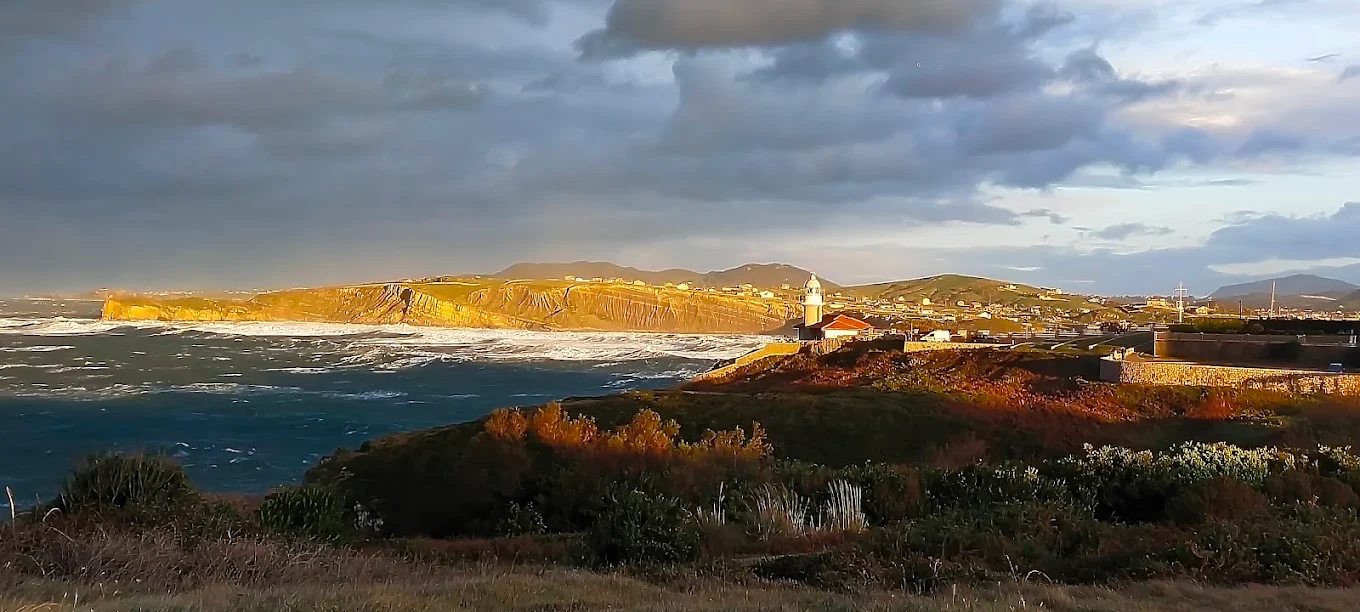 Vista panorámica del Faro de Suances y los acantilados con mar embravecido al atardecer