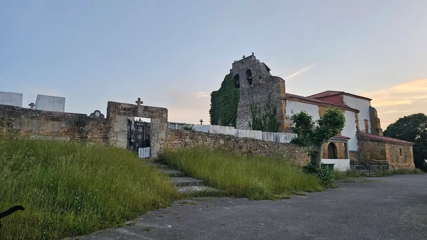 Vista general de la iglesia de San Andrés de Puente Avíos con su espadaña, el atrio y el muro de piedra al atardecer