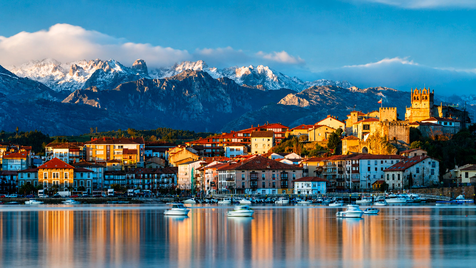 Vista panorámica de San Vicente de la Barquera desde la ría, con el Castillo del Rey, la iglesia de Santa María de los Ángeles y los Picos de Europa nevados al fondo