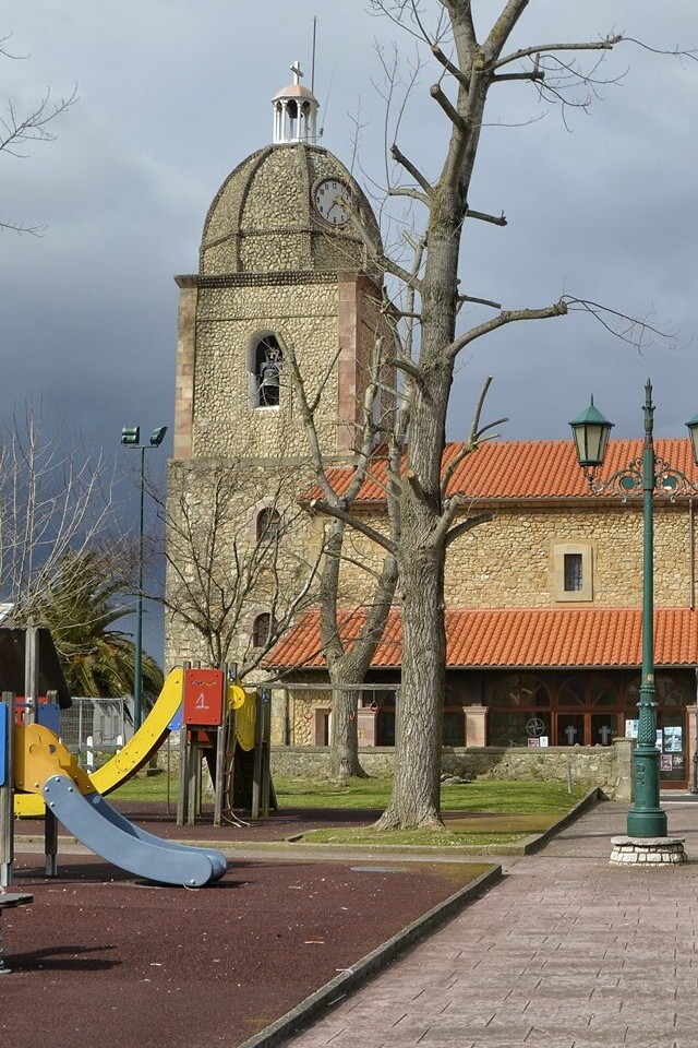 Fachada lateral y torre campanario de la iglesia de Nuestra Señora de las Lindes de Suances, bajo un cielo tormentoso