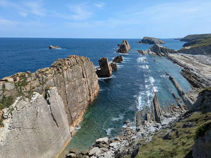 Acantilado con columnas de roca vertical y pequeños islotes alineados en el mar