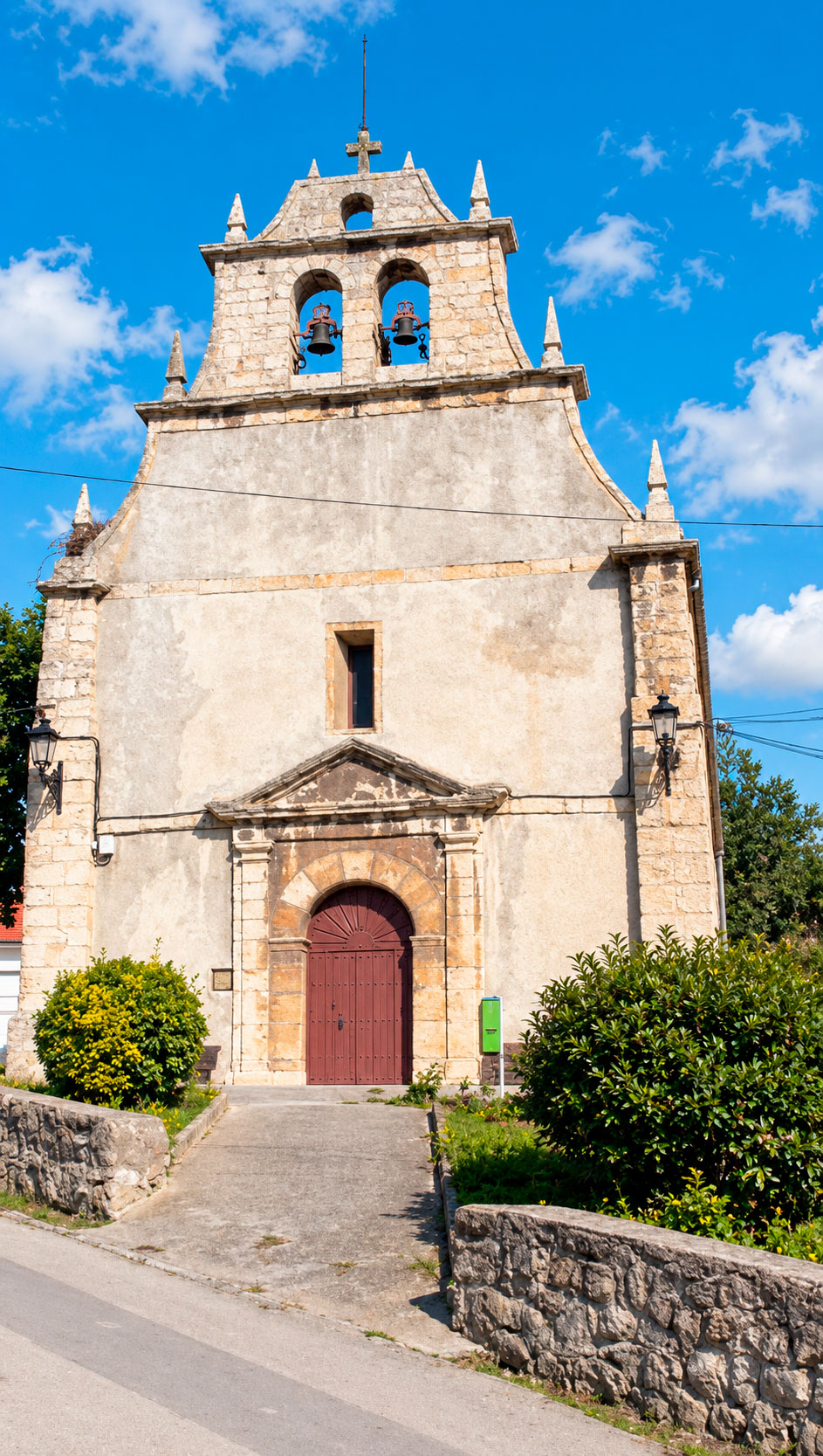 Fachada de la iglesia de San Juan de Cortiguera con el frontón, los pináculos y el campanario de espadaña