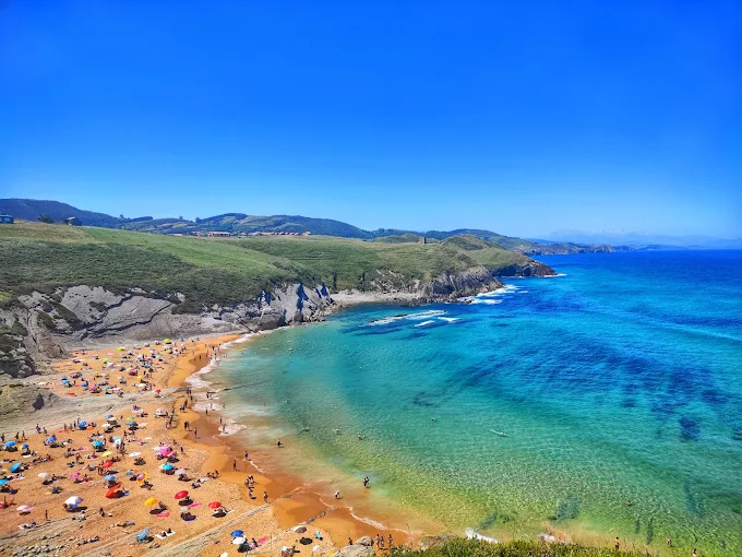 Playa del Sable de Tagle con Bandera Azul y acantilados al fondo