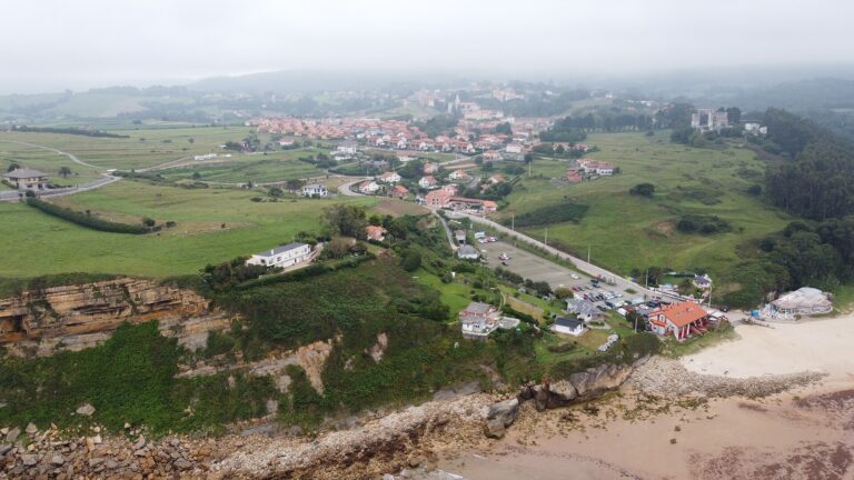 Vista panorámica de Cóbreces desde la playa de Luaña, con el pueblo entre prados y acantilados