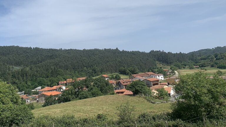 Vista del núcleo rural de La Busta, rodeado de prados y lomas arboladas