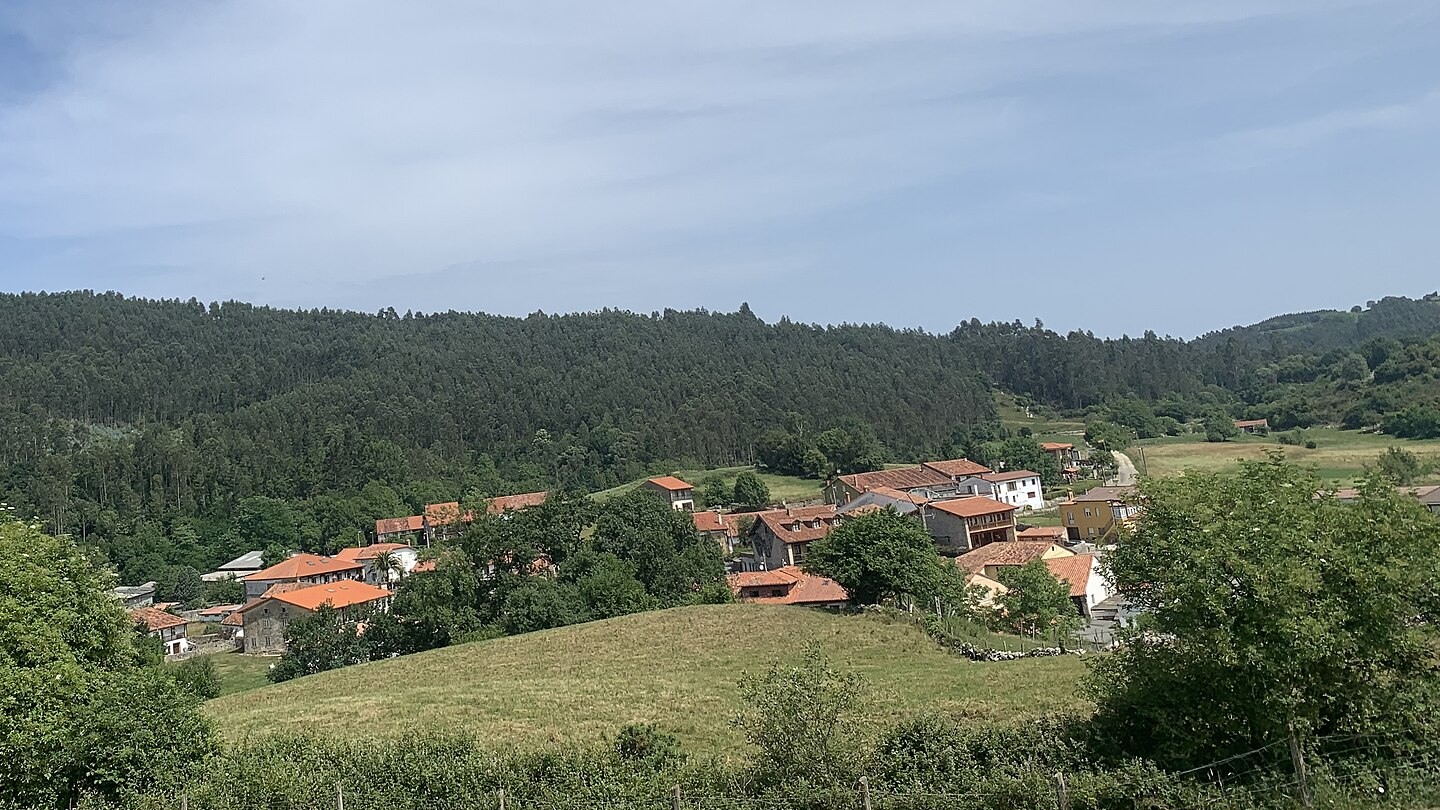 Vista del núcleo rural de La Busta, rodeado de prados y lomas arboladas